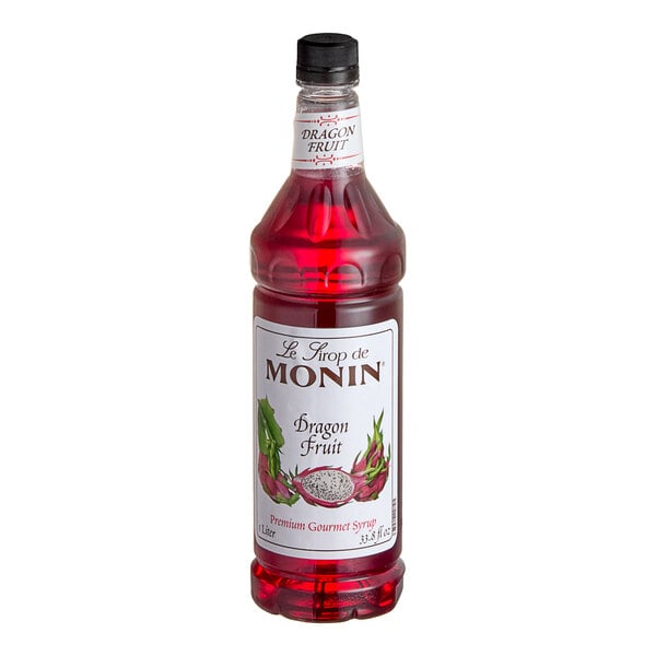 A close up of a bottle of Monin Premium Dragon Fruit flavoring syrup with red liquid inside.