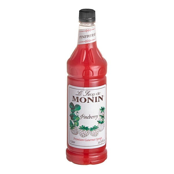 A Monin Premium Pineberry flavoring syrup bottle filled with red liquid.