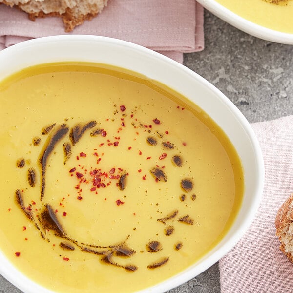 A close up of a bowl of soup with Regal basil leaves sprinkled on top.