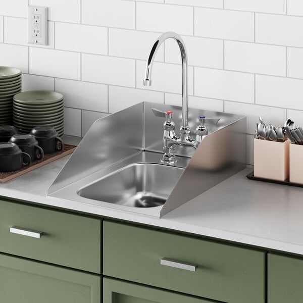 A Waterloo stainless steel drop-in sink with a faucet and side splashes on a green counter.
