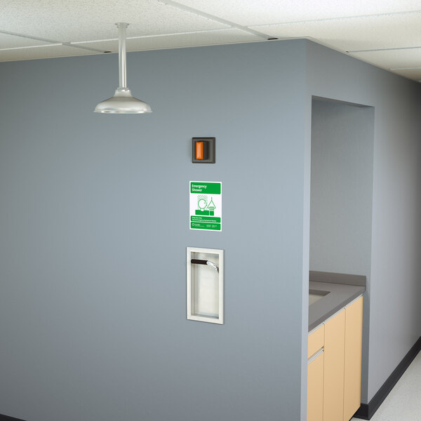 A hallway with a Guardian Equipment Recessed Emergency Shower sign and green light above.
