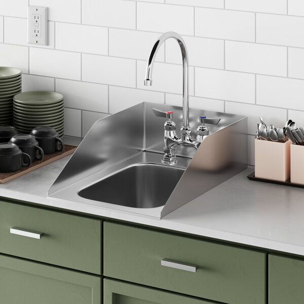 A Waterloo stainless steel drop-in sink with faucets and side splashes in a green counter and cabinet.