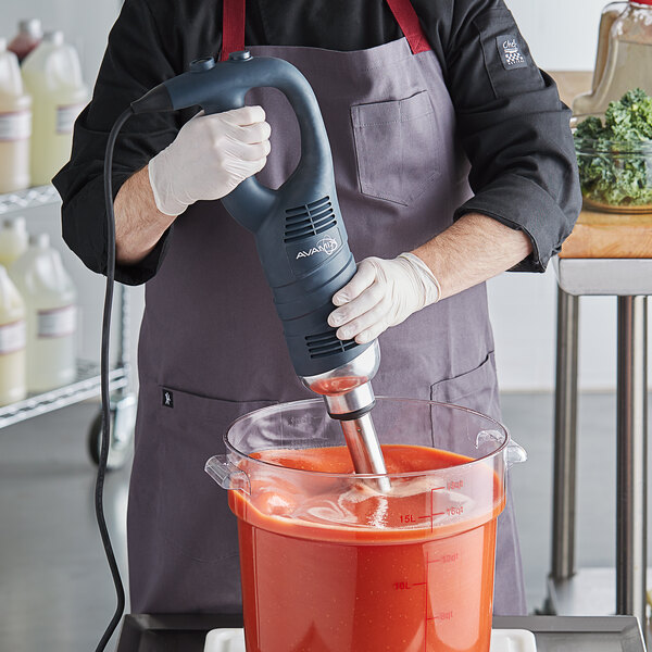 Person using an immersion blender to make a tomato sauce