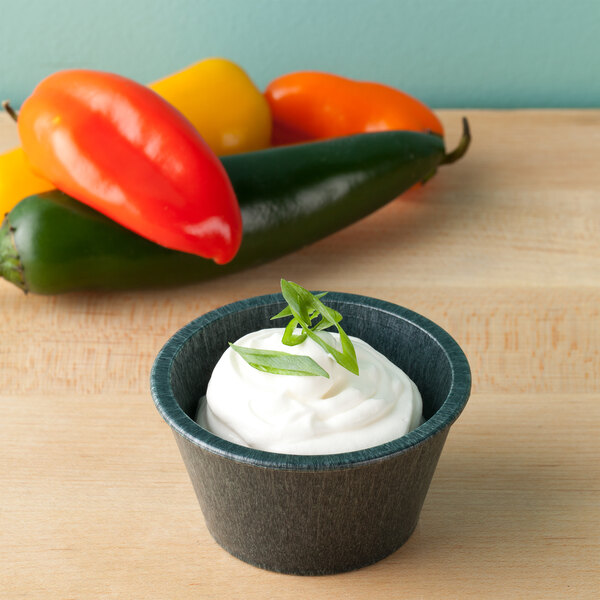 A white ramekin of cream with a green leaf on top.