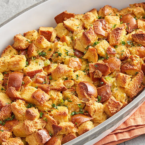 A casserole dish filled with bread stuffing next to a container of Regal Ground Savory Leaves.