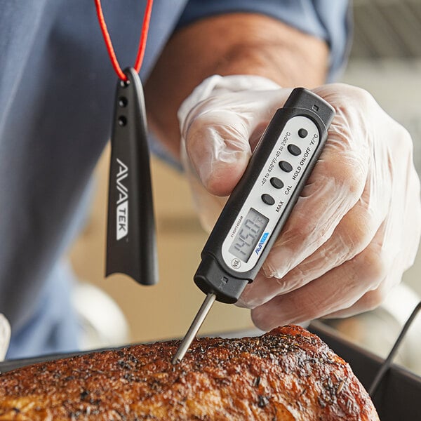 A digital pocket probe thermometer being used to measure the temperature of cooked meat.