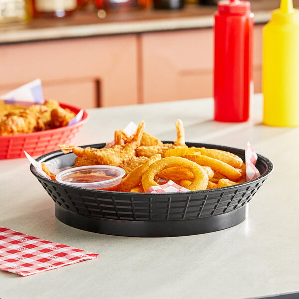 A black Tablecraft diner platter basket filled with fried food on a table.