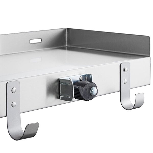 A stainless steel Regency utility shelf with mop and broom holders and hooks.