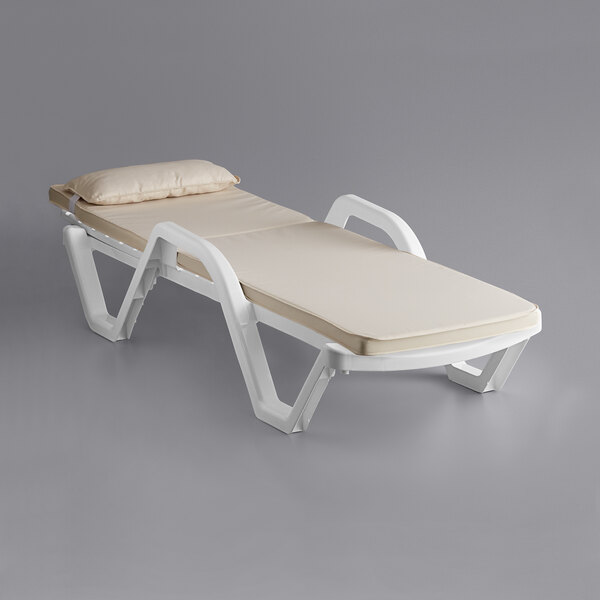 A white Lancaster Table & Seating chaise with a tan cushion and pillow.