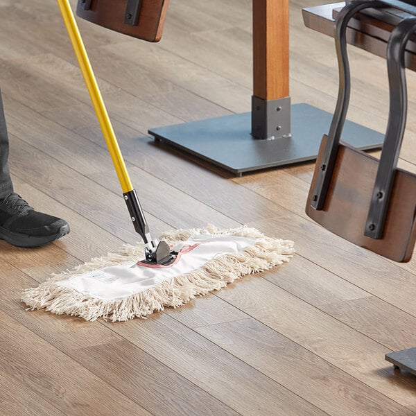 A person using a Choice natural cotton dry mop on a wood floor.