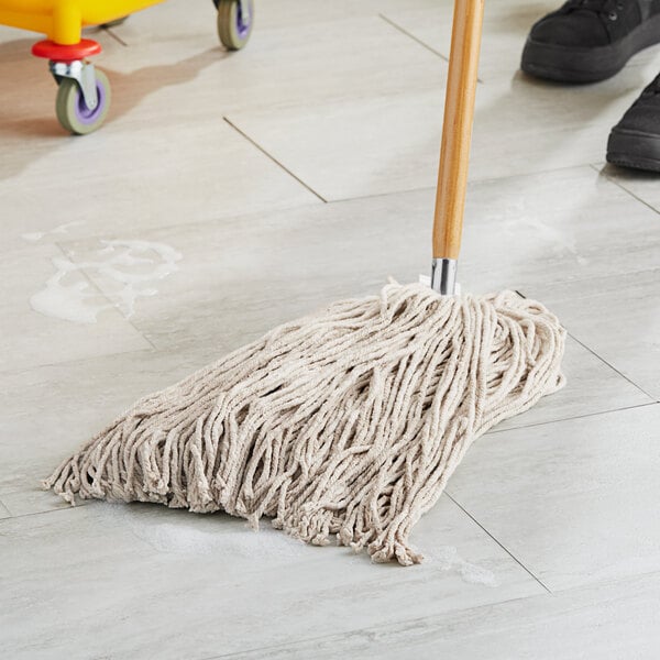 A Lavex natural cotton wet mop head being used to clean a floor.