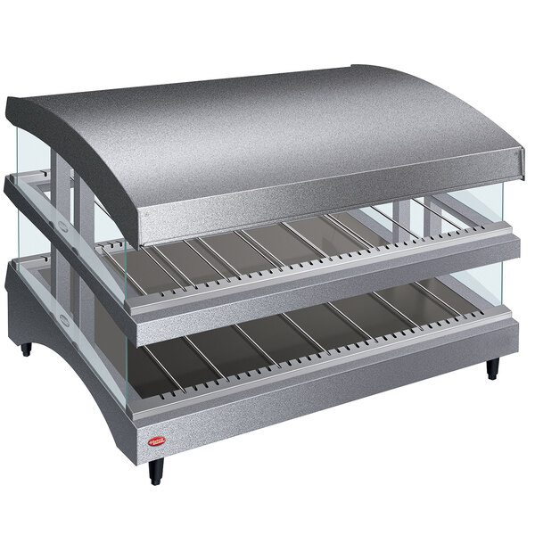 A Hatco countertop food warmer with double shelves and a curved glass top on a bakery counter.