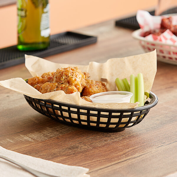 A black oval plastic fast food basket filled with fried chicken on a table.