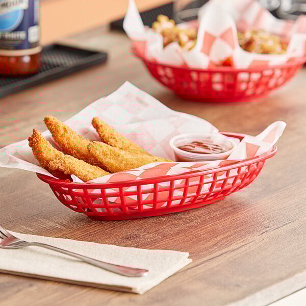 A red oval plastic basket with chicken strips and sauce.