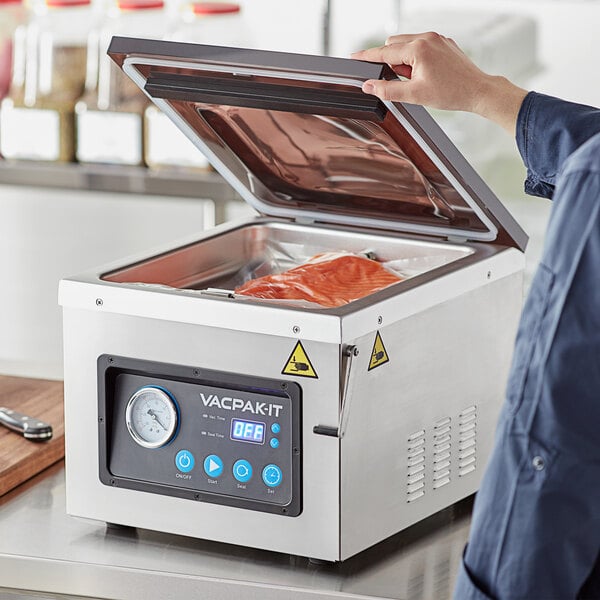 Person lifting lid of VacPak-It chamber vacuum sealer to reveal salmon