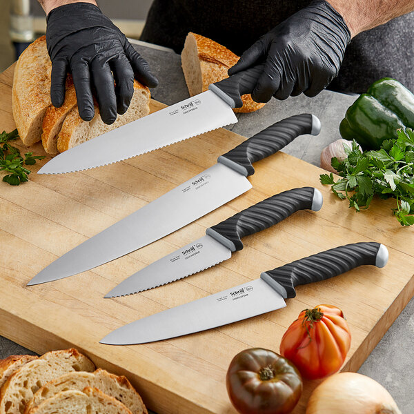 A person in black gloves using a Schraf chef knife to cut bread on a cutting board.