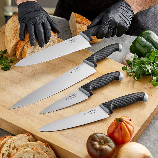 A person in black gloves using a Schraf serrated chef knife to cut bread.