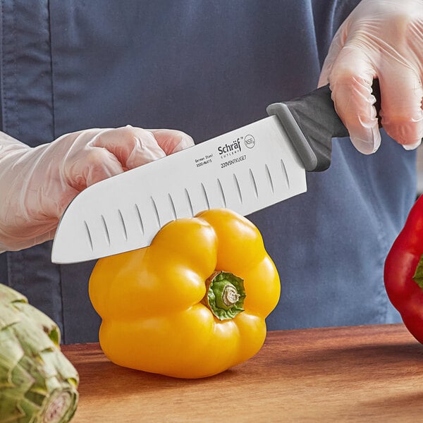 Santoku knife cutting into a yellow bell pepper