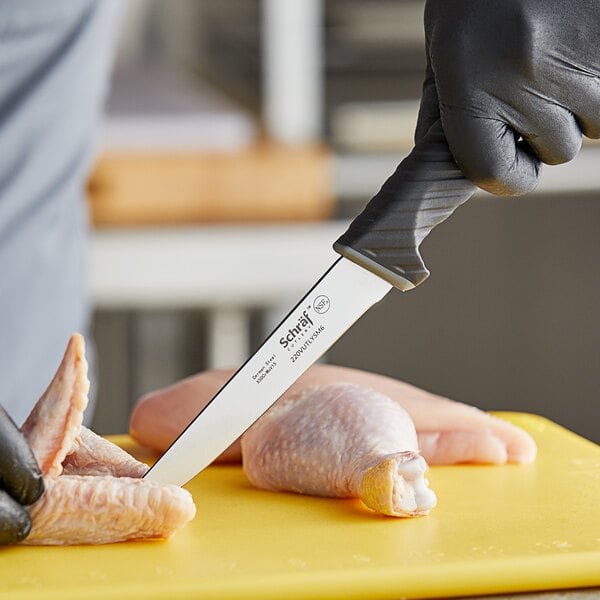 Utility knife slicing through a chicken wing