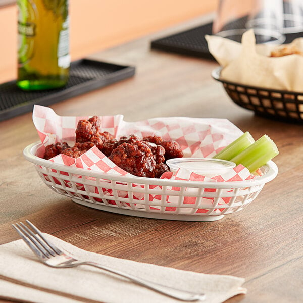 A white oval plastic basket filled with fried chicken and celery.