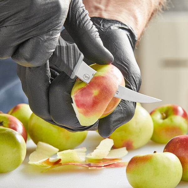 Tourne knife being used to peel the skin off an apple