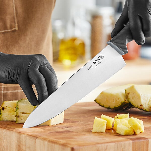 someone using a knife to cut a pineapple near their hands