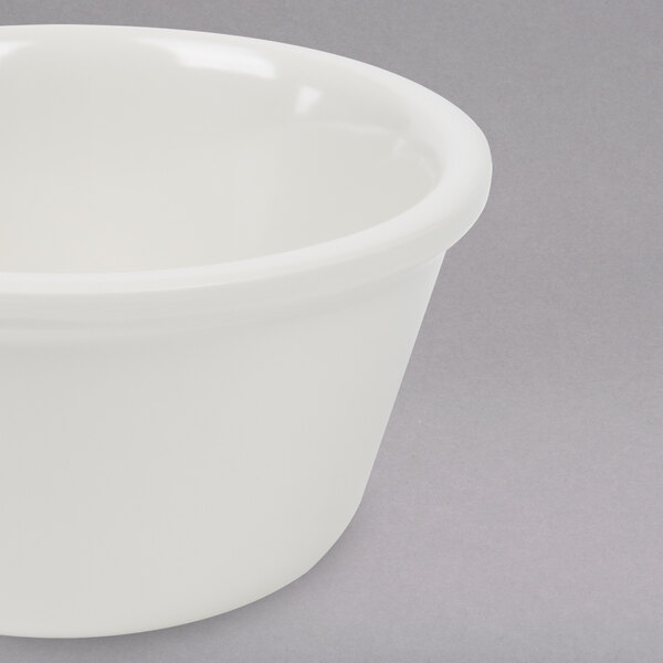 A white Thunder Group Bone Smooth Melamine Ramekin on a gray surface.