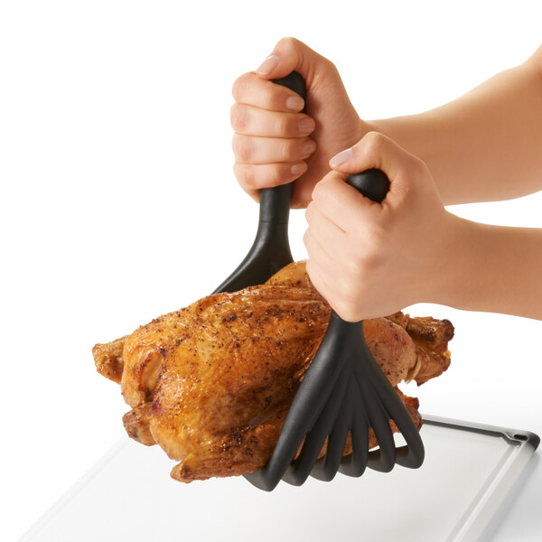 A person using OXO Good Grips nylon meat shredding claws to handle chicken.