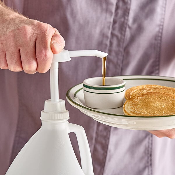 A person using a Tablecraft syrup pump to pour syrup onto pancakes.