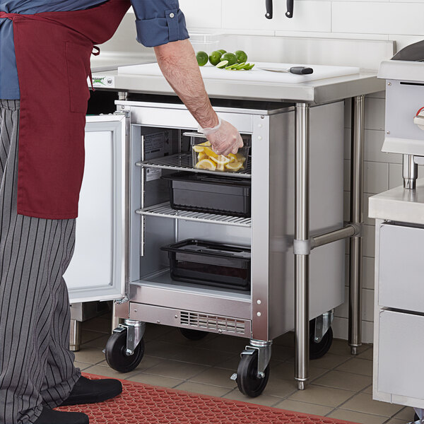 A person in a chef's uniform putting lemons in a Beverage-Air undercounter refrigerator.