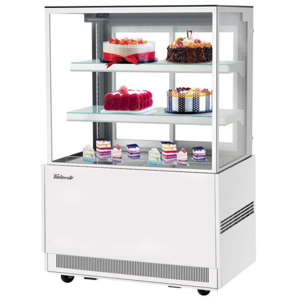 A Turbo Air white refrigerated bakery display case with cakes on it.