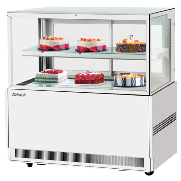 A Turbo Air white refrigerated bakery display case filled with cakes on shelves.