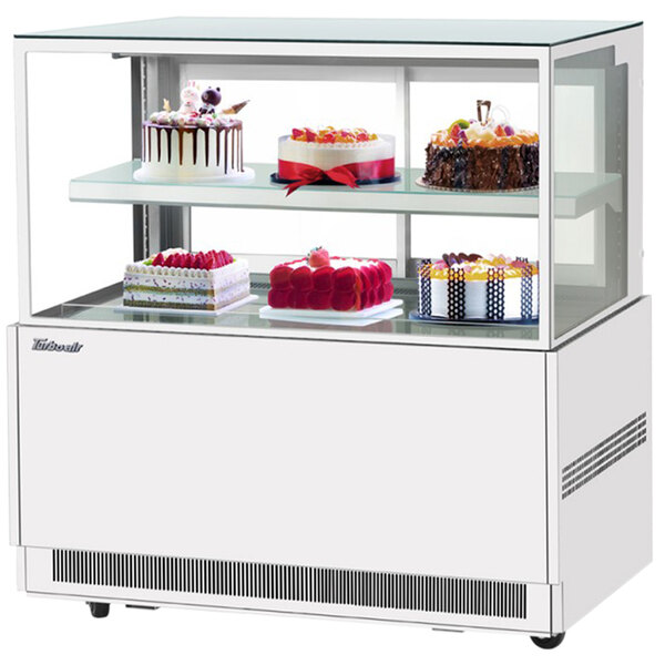 A Turbo Air refrigerated bakery display case with cakes on two tiers.