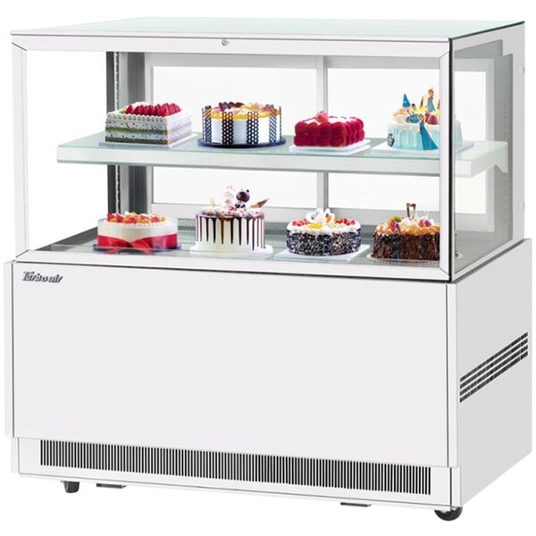 A Turbo Air white refrigerated bakery display case with cakes on it.