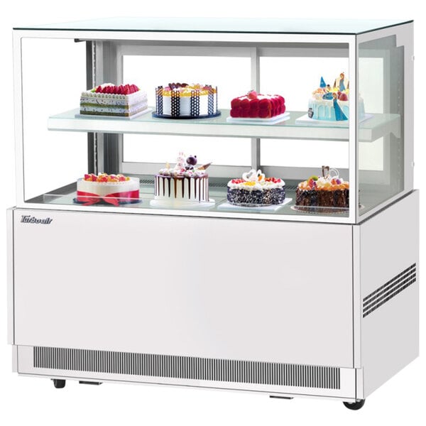 A Turbo Air white refrigerated bakery display case with cakes on it.