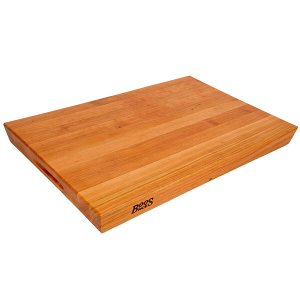 A John Boos cherry wood cutting board with hand grips.