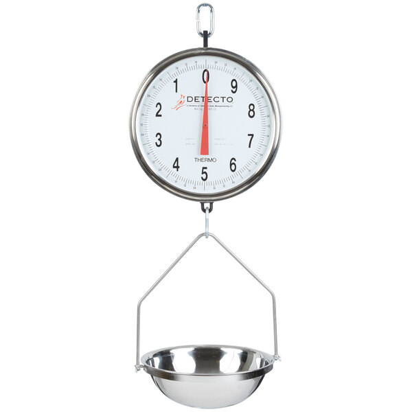 A Cardinal Detecto hanging pan scale with double dials weighing a metal bowl.