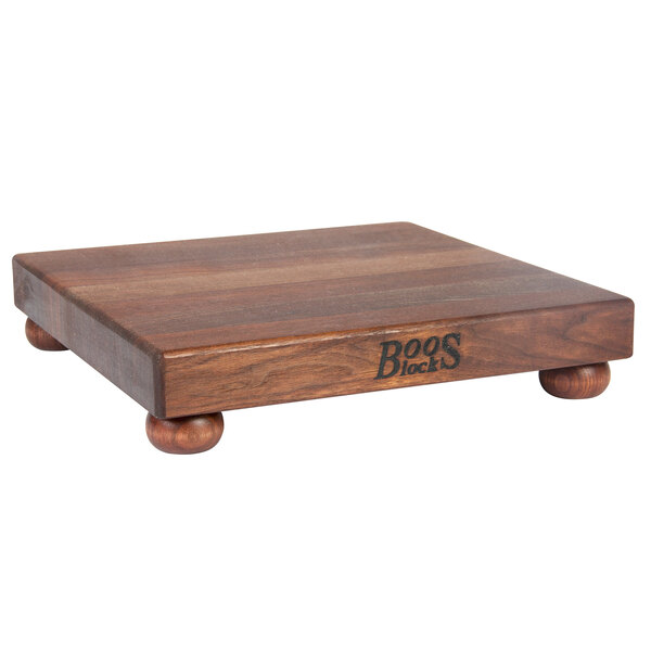 A John Boos black walnut wood display cutting board with bun feet.