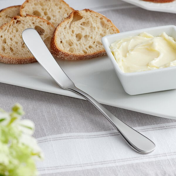 A plate with a butter knife, bread, and butter on it.