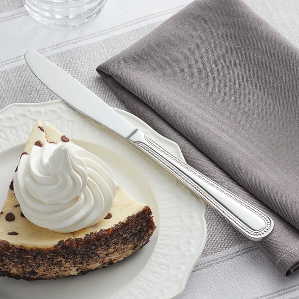 Dessert knife on the edge of a plate next to cheesecake