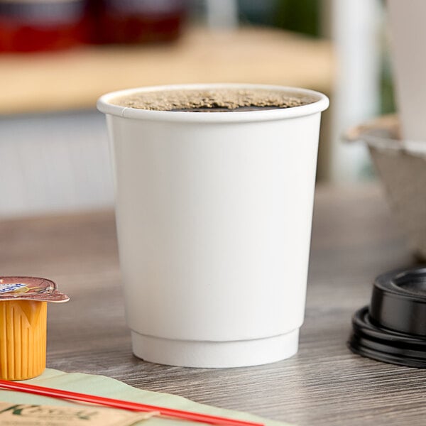 A white Choice double wall paper hot cup with brown liquid in it on a table.