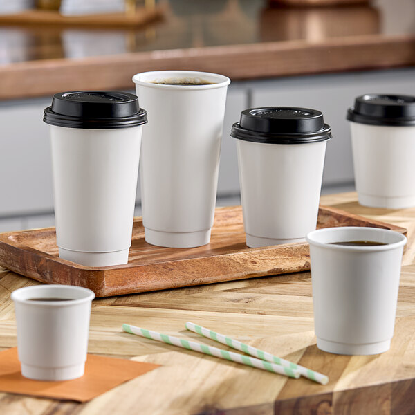 A group of Choice white double wall paper hot cups with black lids.