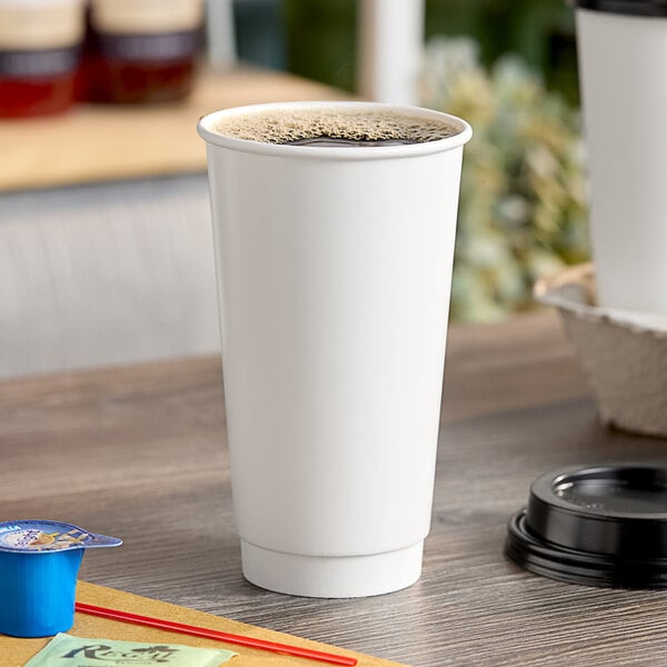 A white Choice paper hot cup with brown liquid on a table.