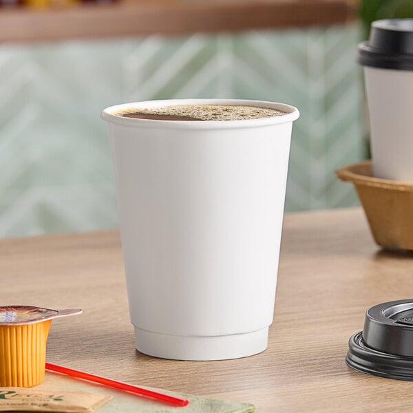 A white Choice double wall paper hot cup filled with brown liquid on a table.