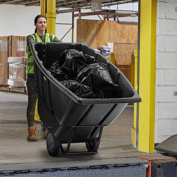 A woman in a safety vest pushing a black Lavex trash cart.