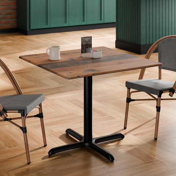 A square table with a textured farmhouse finish and a black pedestal base.