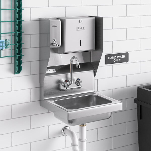 A stainless steel Regency wall mounted hand sink with top mounted soap and paper towel dispensers.
