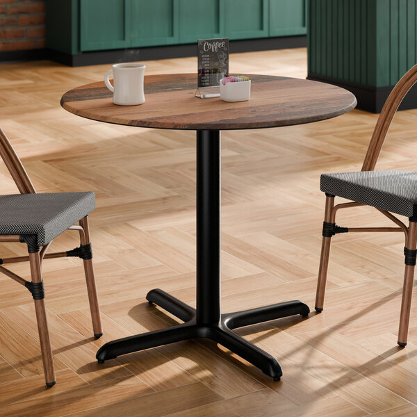 A round table with a textured farmhouse finish and a black pedestal base.