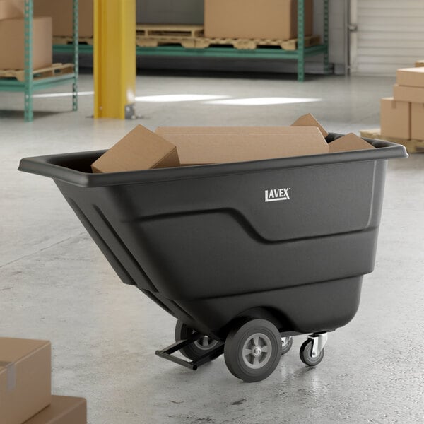 A black Lavex tilt truck or trash cart with a 0.5 cubic yard capacity, shown holding cardboard boxes in a warehouse setting.