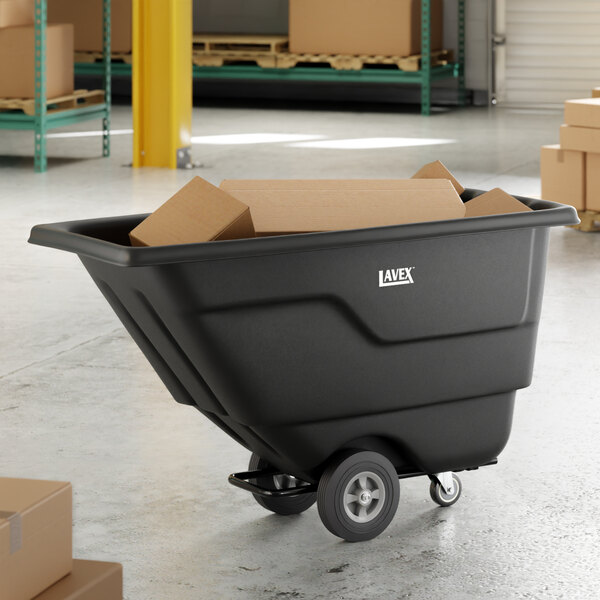 A black Lavex tilt truck or trash cart with a 0.5 cubic yard capacity, shown holding cardboard boxes in a warehouse setting.